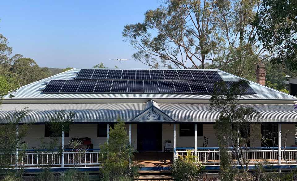 Solar panels on a veranda-style home beneath a clear blue sky.