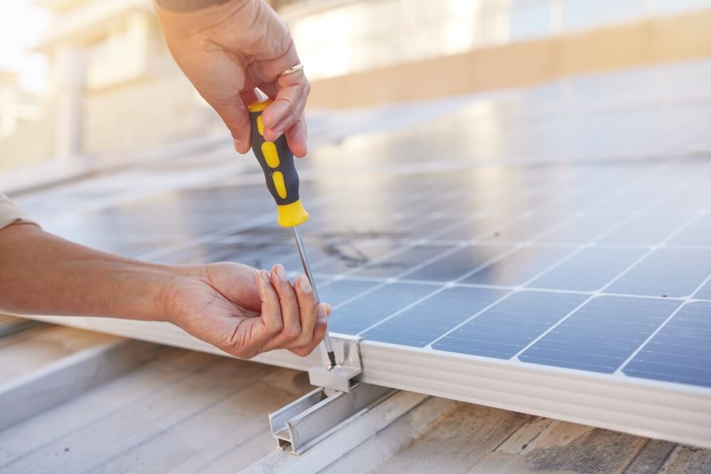 closeup of male hands securing bolt on bracket holding solar panel in place 